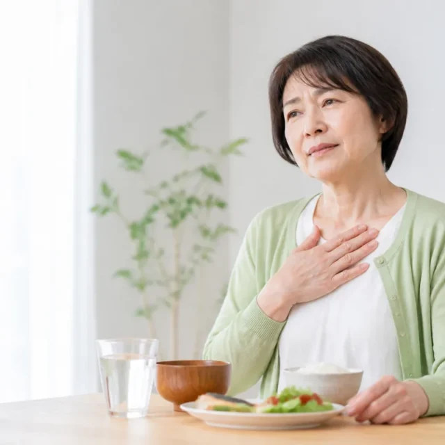 食後の胸やけを感じて胸元に手を添える女性