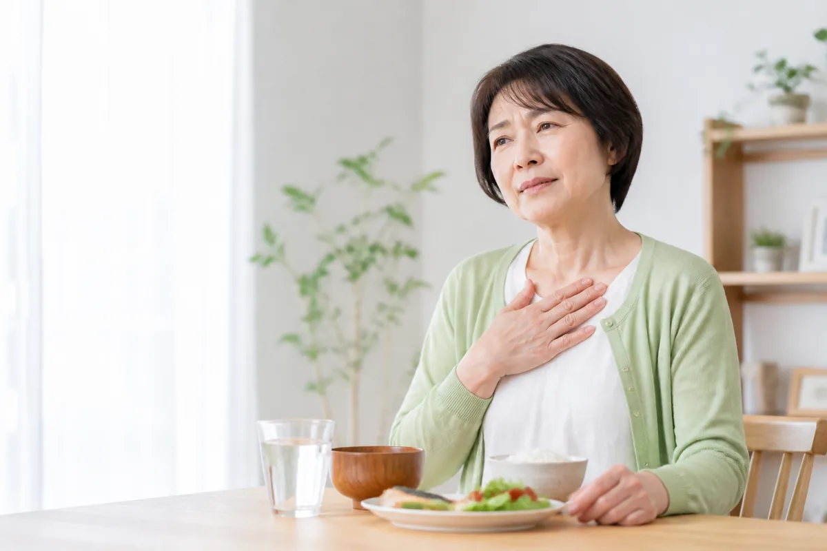 食後の胸やけを感じて胸元に手を添える女性