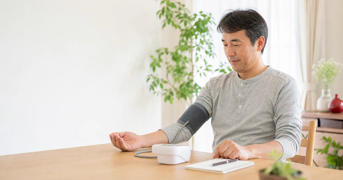 自宅で上腕式血圧計を使って家庭血圧を測る男性